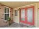 The brick exterior features a decorative red double-door entrance with adjacent window and custom planter at 12371 Talpa St, Spring Hill, FL 34608