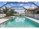 Screened-in pool with spa, red tile trim, white fence, and beautiful blue skies above at 12371 Talpa St, Spring Hill, FL 34608