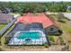 A refreshing inground pool with screened enclosure sits behind a well-maintained home with colorful red roof at 12371 Talpa St, Spring Hill, FL 34608