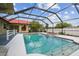 Screened-in pool and jacuzzi with a white fence in the background at 12371 Talpa St, Spring Hill, FL 34608