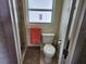 A compact bathroom featuring a toilet and towel rack, with a peek into a tiled shower at 1447 Lemon Bay Dr, Englewood, FL 34223