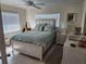 Serene bedroom featuring a queen bed with soft blue bedding, white dresser, and bright window at 1447 Lemon Bay Dr, Englewood, FL 34223