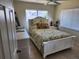 Well-lit bedroom with a white bed featuring colorful tropical-themed bedding, side tables, and tile flooring at 1447 Lemon Bay Dr, Englewood, FL 34223