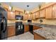 Functional kitchen with granite counters, wooden cabinets, black appliances and tile floors at 1713 Trailwater St, Ruskin, FL 33570