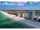 Panoramic aerial showcases beachfront condos along a white sandy beach and clear ocean, offering a serene coastal lifestyle at 17408 Gulf Blvd # 203, Redington Shores, FL 33708