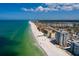 Expansive aerial view displays beachfront condos next to a pristine white sand beach and clear turquoise ocean waters at 17408 Gulf Blvd # 203, Redington Shores, FL 33708
