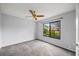 Cozy bedroom with a ceiling fan, carpeted floor, and a large window offering garden views at 1815 Cypress Trace Dr, Safety Harbor, FL 34695