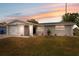 Charming single-story home with a well-maintained lawn, attached garage, and freshly painted exterior, glowing at sunset at 2252 Society Dr, Holiday, FL 34691