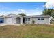 Single-story home features a well-maintained lawn, attached garage, and freshly painted exterior under a bright, cloudy sky at 2252 Society Dr, Holiday, FL 34691