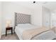 Well-lit bedroom featuring a tufted headboard, neutral color scheme, and cozy furnishings at 2906 Boxwood Grove Row, Wesley Chapel, FL 33543