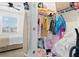 Split image of bedroom with an ironing board and a closet with assorted clothes and accessories at 2906 Boxwood Grove Row, Wesley Chapel, FL 33543