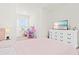 Bright bedroom featuring a white dresser and desk, a large TV, and a plush pink bedspread at 2906 Boxwood Grove Row, Wesley Chapel, FL 33543