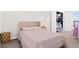 Cozy bedroom featuring a pink upholstered bed, gray nightstand, and walk-in closet with open door at 2906 Boxwood Grove Row, Wesley Chapel, FL 33543