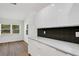 Bright kitchen features white cabinets, modern countertop, black backsplash, and wood flooring at 3151 6Th S Ave, St Petersburg, FL 33712