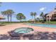 Community pool and hot tub with brick deck, surrounded by lounge chairs and palm trees at 322 Windrush Loop # 22, Tarpon Springs, FL 34689