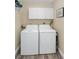 The laundry room features a washer and dryer with white cabinets above on wood look flooring at 322 Windrush Loop # 22, Tarpon Springs, FL 34689