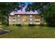 Exterior view of condo featuring large windows and balconies, surrounded by mature trees and a well-manicured lawn at 3399 Mermoor Dr # 301, Palm Harbor, FL 34685