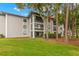 The exterior of the condo building with a small lawn with lots of green grass and plenty of mature trees at 3399 Mermoor Dr # 301, Palm Harbor, FL 34685