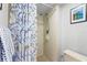 The walk-in shower has cream tiling and blue seashell and coral patterned shower curtain at 3399 Mermoor Dr # 301, Palm Harbor, FL 34685