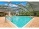 Community pool featuring a screened enclosure, blue water, and patio area at 3399 Mermoor Dr # 301, Palm Harbor, FL 34685