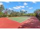 Community tennis court featuring red and green surface surrounded by fencing at 3399 Mermoor Dr # 301, Palm Harbor, FL 34685