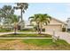 Charming front exterior with mature palms, paver driveway, lush lawn and a welcoming double door entry at 4138 Saltwater Blvd, Tampa, FL 33615