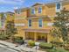 Two-story townhome with a covered porch, outdoor seating, and manicured landscaping for a welcoming appeal at 456 Bayou Village Dr, Tarpon Springs, FL 34689