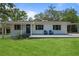 Charming single-story home featuring a well-maintained lawn, blue door, and an inviting front porch with two chairs at 608 Betmor Ln, Palm Harbor, FL 34683
