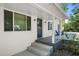 Inviting front porch with stylish blue door, concrete steps, and shade trees at 608 Betmor Ln, Palm Harbor, FL 34683