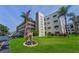 Well-maintained exterior of building, featuring an American flag, sign, palm trees, and attractive landscaping at 6190 80Th N St # 411, St Petersburg, FL 33709