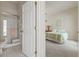 Bright bathroom featuring a glass shower, toilet, and neutral tile, leading into a cozy bedroom at 7206 River Country Dr, Weeki Wachee, FL 34607