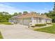 Side view of a home with a three-car garage and lush landscaping at 7206 River Country Dr, Weeki Wachee, FL 34607