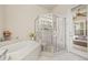 Clean and comfortable main bathroom with bathtub and glass shower, with view to sunroom at 7206 River Country Dr, Weeki Wachee, FL 34607