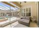 Cozy patio with double chaise lounge, window shutters, and view to pool and courtyard through glass panels at 7206 River Country Dr, Weeki Wachee, FL 34607
