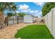 A backyard featuring artificial grass, rock landscaping, a storage shed, and a fenced perimeter at 7909 Canna Dr, Port Richey, FL 34668