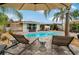 A picturesque poolside view with lounge chairs, umbrellas, and lush palm trees for relaxation at 7909 Canna Dr, Port Richey, FL 34668