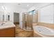 Bright bathroom with a glass shower, garden tub, double sinks, and wood cabinets at 8015 Hampton Glen Dr, Tampa, FL 33647
