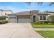 Charming home featuring a three-car garage, stone accents, and neatly landscaped front yard at 8015 Hampton Glen Dr, Tampa, FL 33647