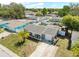 Aerial view of a single Gathering home featuring a palm tree, tidy landscaping, and a large driveway at 9126 Greenbriar Ln, Port Richey, FL 34668