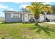 Charming home featuring a well-manicured lawn, a palm tree and a cozy front porch at 9126 Greenbriar Ln, Port Richey, FL 34668