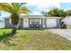 Charming home featuring a well-manicured lawn, a palm tree and a cozy front porch at 9126 Greenbriar Ln, Port Richey, FL 34668