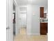 Hallway view of bathroom with tiled floor and open door with kitchen and cabinetry at end of the hall at 9126 Greenbriar Ln, Port Richey, FL 34668
