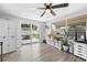 Bright living room with wood-look floors, ceiling fan, and sliding glass doors leading to the backyard at 9126 Greenbriar Ln, Port Richey, FL 34668