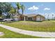 Inviting single-story home featuring a lush lawn, palm trees, and a two-car garage at 10149 Briar Cir, Hudson, FL 34667