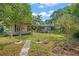 Large backyard with a lush green lawn, mature trees, and a stone path leading to the house at 1021 15Th St, Palm Harbor, FL 34683