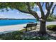 Serene view of the beach with a bench, pier, and clear blue water under a partly cloudy sky at 10408 Butia Pl, Tampa, FL 33618