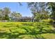 Large grassy backyard featuring a screened-in pool area, mature trees, and a well-maintained lawn at 11203 Killearn Ct, Riverview, FL 33569