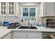 Close up of a large kitchen sink with white cabinets and updated fixtures at 11203 Killearn Ct, Riverview, FL 33569