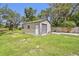 A practical storage shed with a roll-up door in a grassy backyard setting at 11203 Killearn Ct, Riverview, FL 33569