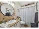 Bright bathroom featuring a granite countertop, round mirror, and shower with a curtain at 11446 Sinatra Ct, New Port Richey, FL 34654